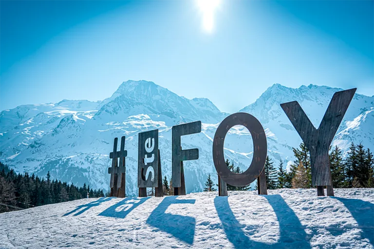 L’enseigne Sainte-Foy se détache devant les montagnes enneigées.