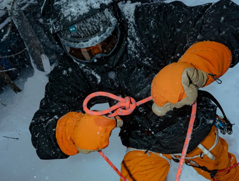 Un participant manipule une corde avec des gants lors d’un atelier en montagne.