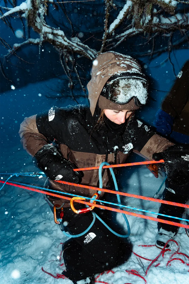 Un participant équipé d’un casque manipule des cordes lors d’un exercice dans la neige.