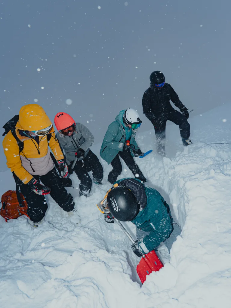 Des participants creusent ensemble dans la neige avec des pelles.