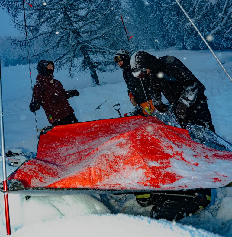 Des participants préparent un dispositif de secours orange dans la neige.