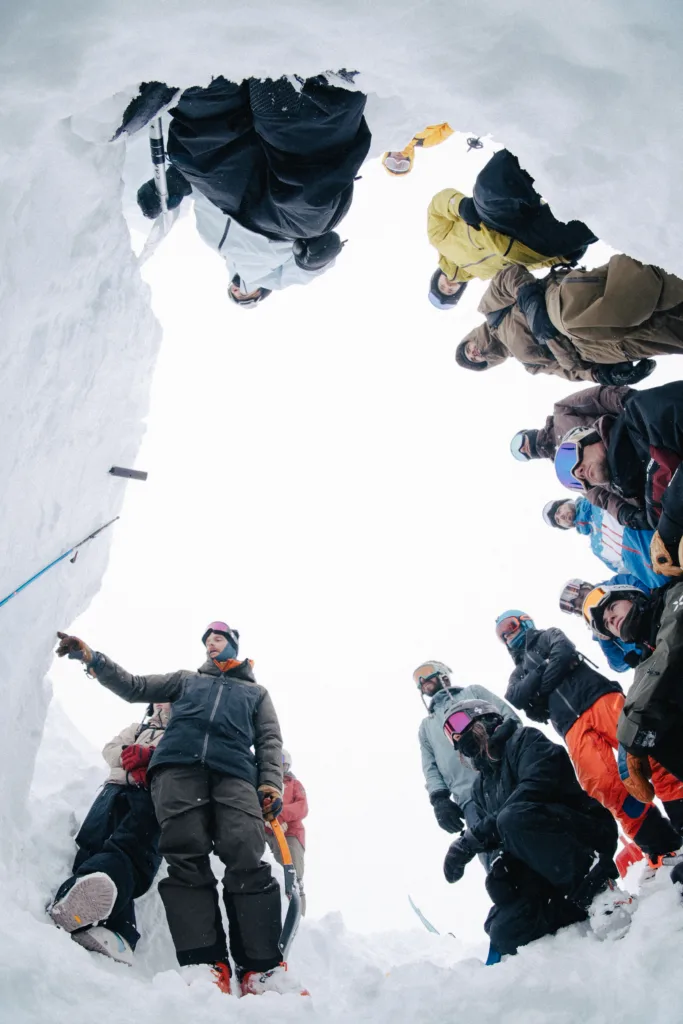 Un intervenant donne des explications à un groupe réuni dans la neige.