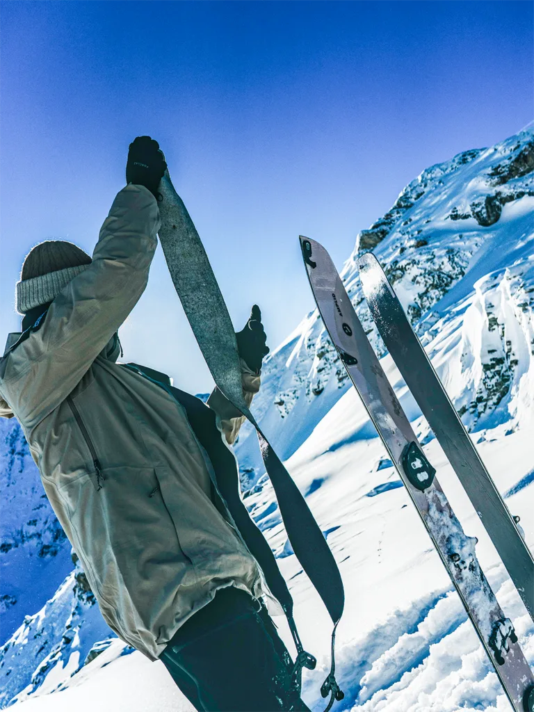 Un participant porte ses skis sur l’épaule dans une pente enneigée.