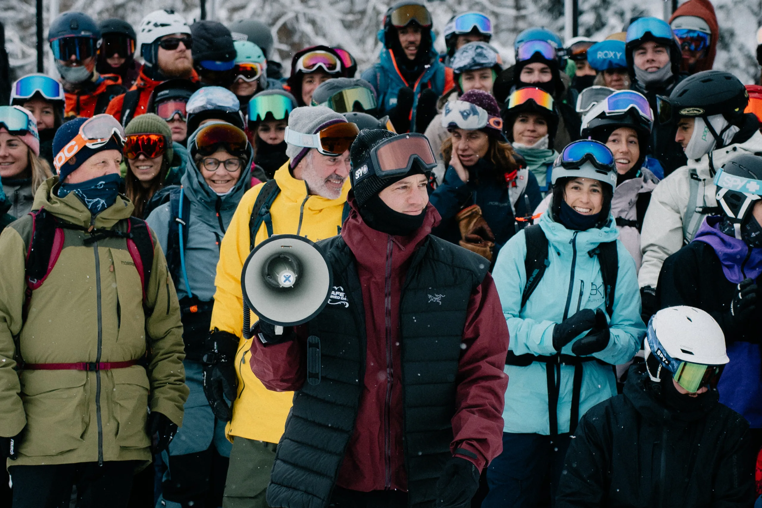 Un intervenant au mégaphone s’adresse aux participants réunis dans la neige.