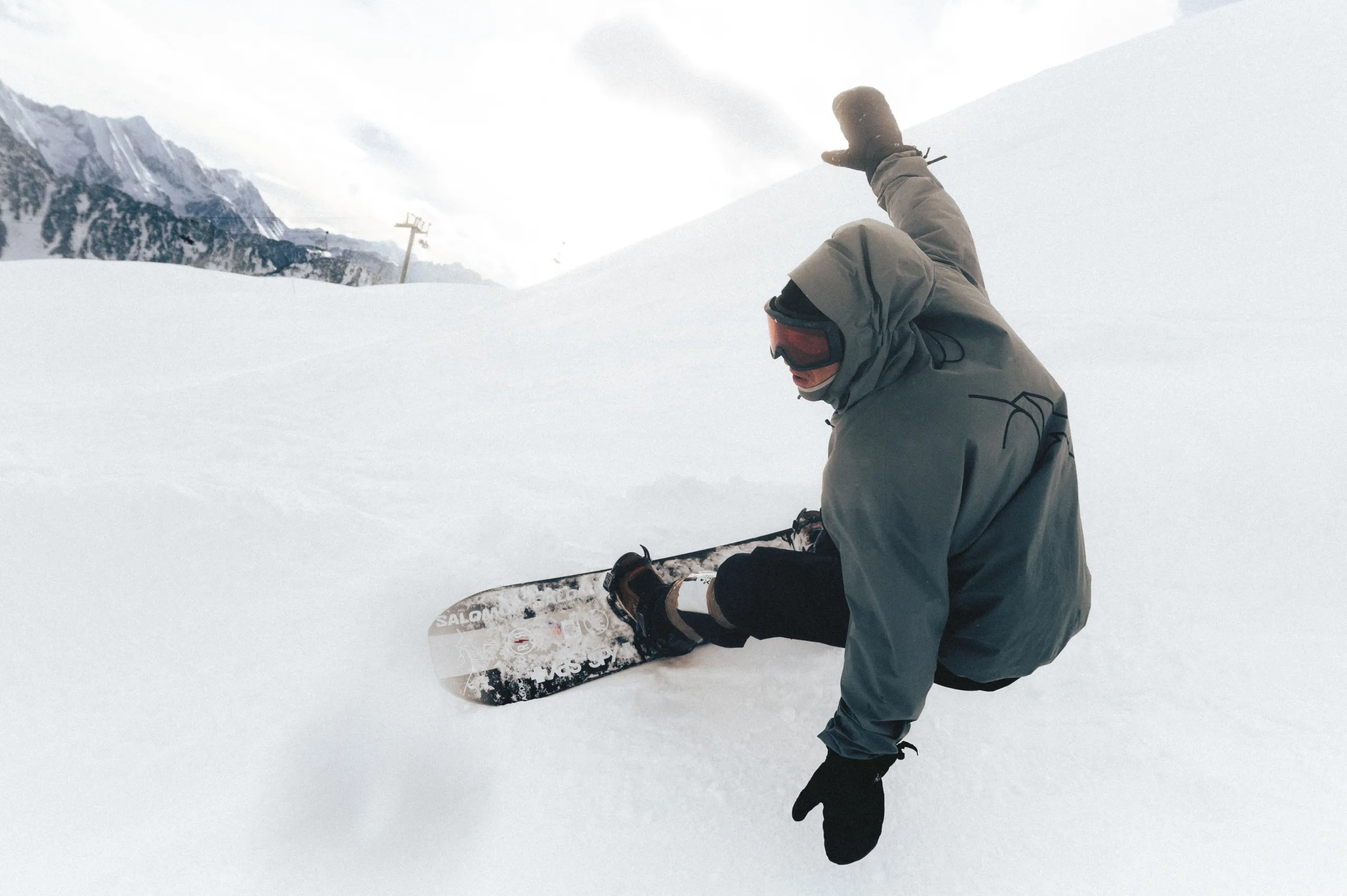 Un snowboardeur prend un virage relevé, une main près de la neige.