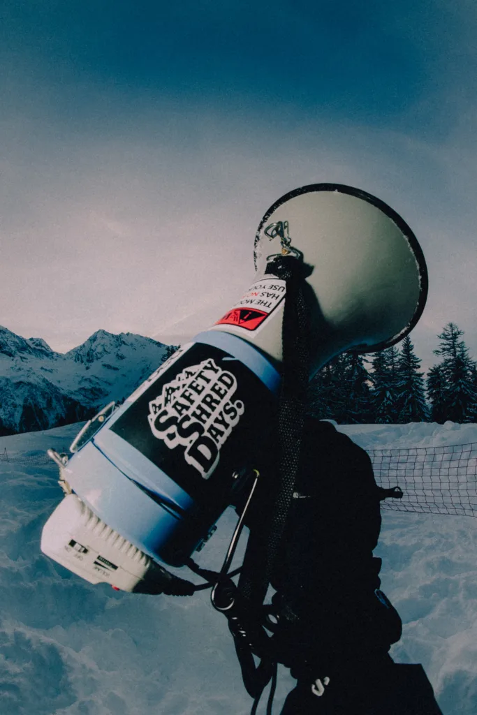 Un snowboardeur porte sa planche sur l’épaule en montagne.